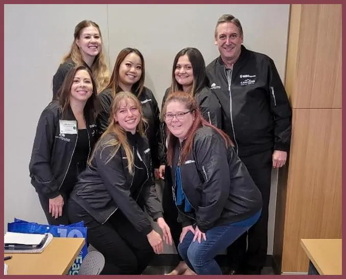 Dental team members in dark uniforms posing together at Jordan Landing Smiles office.